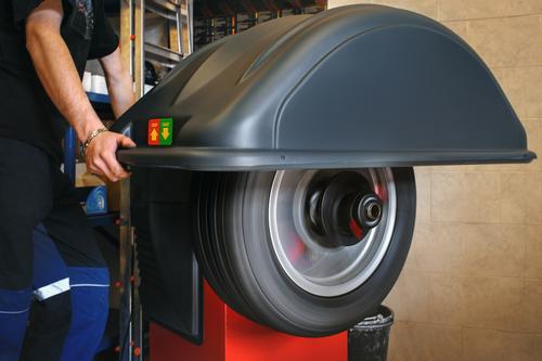 Mecánico trabajando con balanceadora de ruedas digital computarizada con un ciclo único totalmente automático en el servicio de neumáticos.