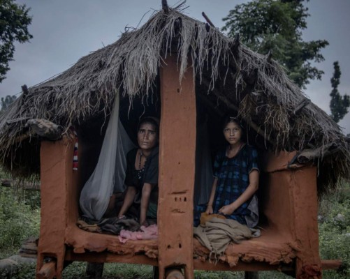 Mangu Bika, 14. “I was in Gujarat in India working during my first year of menstruation. I didn’t observe chaupadi there. Things are different here.”'The first time I went into a chaupadi I was scared of snakes. But now, more than snakes, I am scared of men; I am scared of getting kidnapped. I am really worried about what will happen to me after marriage. I want to grow up and be a teacher because I like going to school. Because when we go to school, we all sit together and their are no rules there or any discrimnation against the menstruating woman.'Chandra Tiruva, 34, and her child, Madan, 2, share the chaupadi with Mangu. 'It is the traditional belief that our 'kul devtaa' [house god] will be angered, so I was sent to chaupadi. I don't like being here but there is a lot of force. My mother in law forces me, but what can I do. She looks after my other three children during this period. But my mother in law even makes my two year old child observe chaupadi just because he sleeps with me.'Surkhet district, Nepal