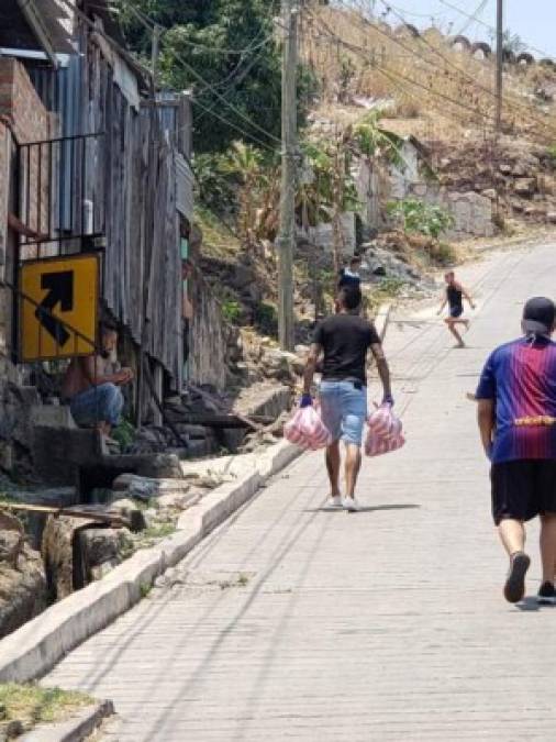 El futbolista del Marathón caminando por las calles en las que se crió para entregar las donaciones.