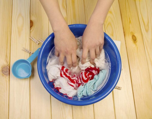 Women&#39;s hands wash clothes in blue pelvis, close up