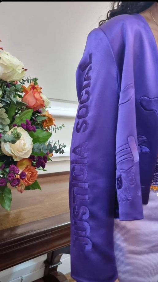 En la otra manga se lee justicia social. La chaqueta también estaba bordada con un paisaje rural, que muestra a una mujer campesina, un burro y una cerca.