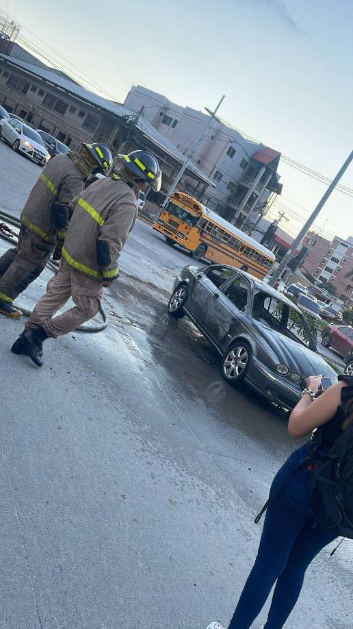 Dos elementos del cuerpo de Bomberos inspeccionan el carro tras haber controlado las llamas.