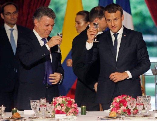 Colombian President Juan Manuel Santos (L) toasts with French President Emmanuel Macron during a state dinner at the Elysee Palace, in Paris, on June 21, 2017. / AFP PHOTO / POOL / JEAN-PAUL PELISSIER