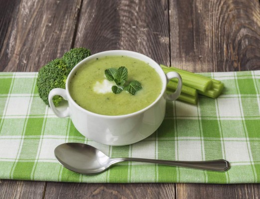 Broccoli soup puree with mint and ricotta cheese on the dark wooden background.
