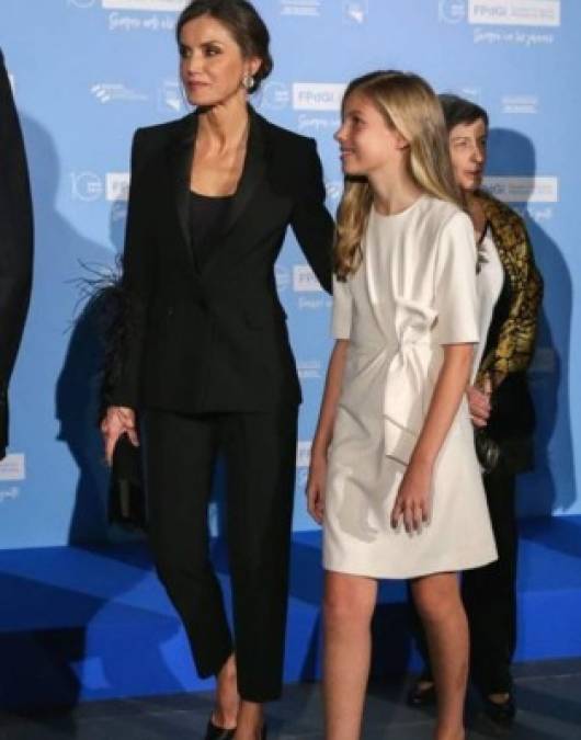 Para no robar el protagónico a Leonor, la infanta Sofía lució un vestido blanco, mientras que la reina Letizia optó por un traje dos piezas en negro con un toque original: mangas adornadas con plumas.