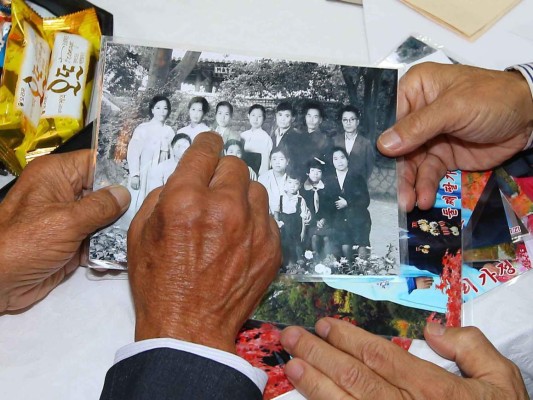 North Korean Sim Yeong-Sik, 85, points on his family picture to show his South Korean relatives during a separated family reunion meeting at the Mount Kumgang resort on the North's southeastern coast on October 20, 2015. Nearly 400 mostly elderly and frail South Koreans began a tearful, emotionally fraught reunion with family members in North Korea, more than 60 years after they were separated by the Korean War. REPUBLIC OF KOREA OUT NO ARCHIVES RESTRICTED TO SUBSCRIPTION USE AFP PHOTO / YONHAP