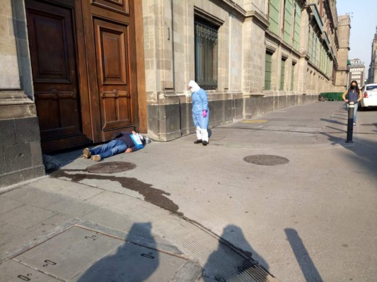 Un hombre con COVID-19 se tumba frente al Palacio Nacional de México
