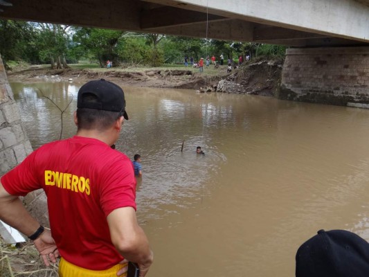 Bomberos y otros voluntarios buscan los cuerpos con la ayuda de equipo especial en los ríos de Nueva Arcadia, Copán.