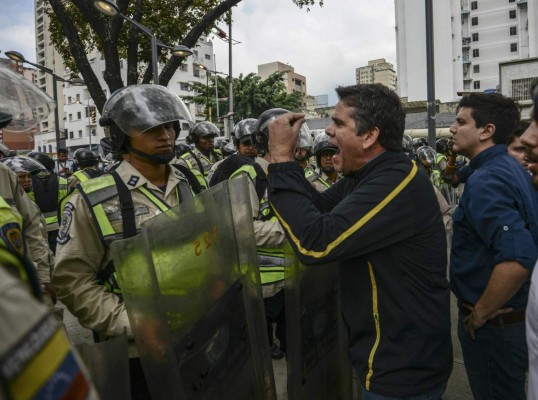 Venezuelan opposition deputie Rafael Guzman (C), confronts National Guard personnel during a protest in front of the National Attorney's General office building in Caracas on March 31, 2017. Venezuela's attorney general Luisa Ortega surprisingly broke ranks with President Nicolas Maduro on Friday, condemning recent Supreme Court rulings that consolidated the socialist president's power as a 'rupture of constitutional order.' / AFP PHOTO / JUAN BARRETO