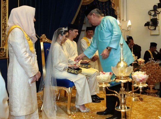 This handout photograph made available on August 14, 2017 by the Royal Press Office shows Dennis Muhammad Abdullah (sitting at R) of the Netherlands with his bride Princess Tunku Tun Aminah Sultan Ibrahim (sitting at L), receive blessing from the father, Johor Sultan Ibrahim Sultan Iskandar (R), during a wedding function at Istana Besar in Johor Bahru. The daughter of one of Malaysia's most powerful sultans married her Dutch fiance on August 14 in a ceremony steeped in centuries of tradition during a day of lavish celebrations. / AFP PHOTO / ROYAL PRESS OFFICE / HANDOUT / -----EDITORS NOTE --- RESTRICTED TO EDITORIAL USE - MANDATORY CREDIT 'AFP PHOTO / ROYAL PRESS OFFICE' - NO MARKETING - NO ADVERTISING CAMPAIGNS - DISTRIBUTED AS A SERVICE TO CLIENTS - NO ARCHIVES