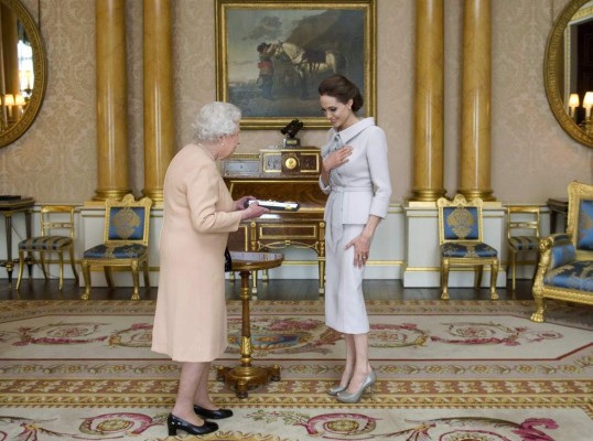Actress Angelina Jolie is presented with the Insignia of an Honorary Dame Grand Cross of the Most Distinguished Order of St Michael and St George, by Britain's Queen Elizabeth in the 1844 room at Buckingham Palace in London October 10, 2014. REUTERS/Anthony Devlin/pool (BRITAIN - Tags: ENTERTAINMENT ROYALS)