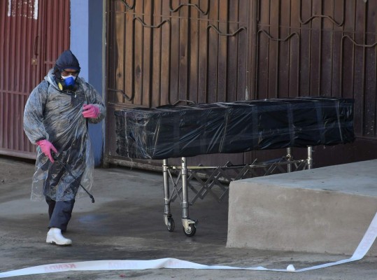 Empleados de una funeraria retiran el cuerpo sin vida de un hombre que permaneció durante horas abandonado en una calle, este domingo en Cochabamba (Bolivia). EFE/Jorge Ábrego