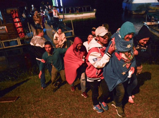 Survivors clad in blankets arrive onshore after being rescued from the tourist boat Almirante in the Reservoir of Penol in Guatape municipality in Antioquia on June 25, 2017.At least nine people were dead and 28 missing after a tourist boat sank in a reservoir in northwestern Colombia on June 25, a regional official said. / AFP PHOTO