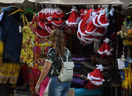 A passer-by looks at a stall in a popular fair in downtown Rio de Janeiro, Brazil, on December 20, 2016.The city of Rio is struggling in the aftermath of hosting the 2014 football World Cup and this year's Olympics, while the Rio state government is nearly bankrupt and the entire country is going through hard economic times. / AFP PHOTO / Vanderlei ALMEIDA