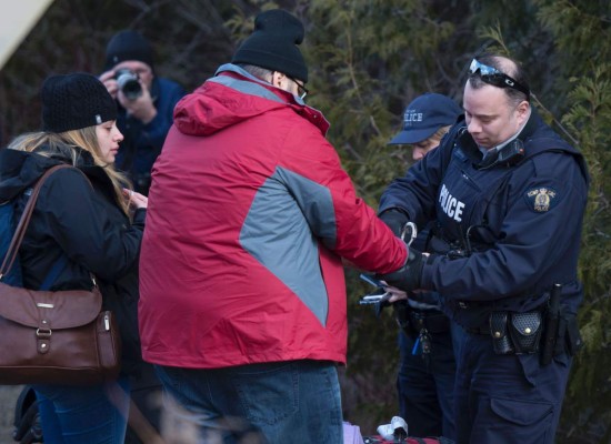 A man who claimed to be from Turkey is handcuffed by the RCMP as his wife watches after crossing the US/Canada border February 27, 2017, in Champlain, New York. There continues to be an increasing number of people crossing the US border into Canada illegally. / AFP PHOTO / Don EMMERT