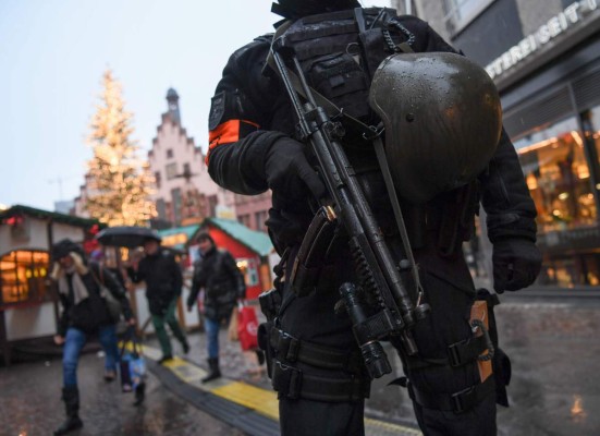 A policeman with machine gun stands guard at the Christmas market at the Roemerberg in the centre of Frankfurt am Main, western Germany, on December 22, 2016, as security measures are taken after the deadly Christmas market attack in Berlin.As police hunt for Tunisian Anis Amri, the top suspect in Berlin's Christmas market attack, public anger has grown over a catalogue of failures that allowed him to evade arrest or deportation. / AFP PHOTO / dpa / Arne Dedert / Germany OUT