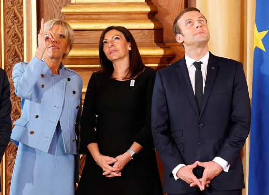 Brigitte Trogneux (L), wife of French President Emmanuel Macron (R), stands with Paris Mayor Anne Hidalgo during an official ceremony at Paris' city hall after his formal inauguration as French President on May 14, 2017 in Paris. / AFP PHOTO / POOL / CHARLES PLATIAU