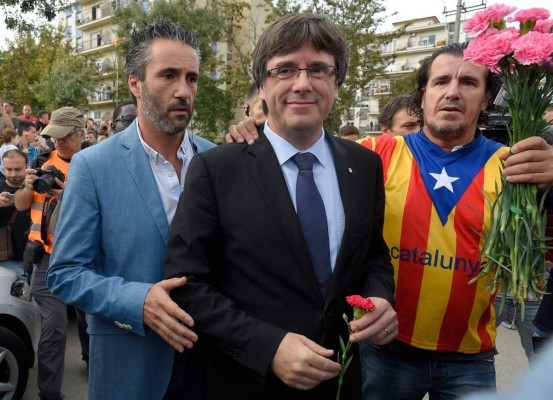 Catalan president Carles Puigdemont (C) holds a carnation in Sant Julia de Ramis, on October 01, 2017, during a referendum on independence for Catalonia banned by Madrid. / AFP PHOTO / LLUIS GENE