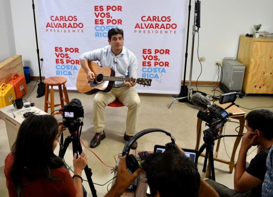 Costa Rican presidential candidate for the Citizen Action Party (PAC), Carlos Alvarado plays the guitar during a Facebook Live broadcast in San Jose, Costa Rica, on March 29, 2018. Costa Rica faces a presidential runoff between Fabricio Alvarado, a 43-year-old lawmaker, pastor and singer with the National Restoration Party, and Carlos Alvarado, a former minister from the leftist ruling party. Despite the shared last name, the two men are unrelated. / AFP PHOTO / Ezequiel BECERRA