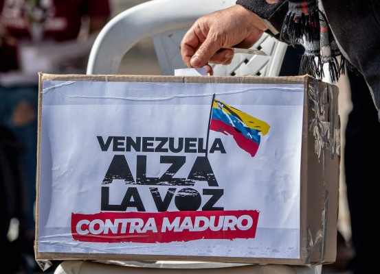 A Venezuelan migrant casts his vote during a 'popular consultation' called by Venezuelan opposition leader Juan Guaido in Bogota, on December 12 , 2020. - Guaido is playing his last card this Saturday to keep himself afloat in Venezuela's political scene, by calling a referendum-style 'popular consultation', with which he hopes a disappointed opposition will return to the streets to express its discontent against President Nicolas Maduro. (Photo by Juan BARRETO / AFP)