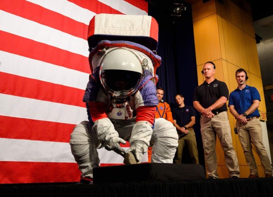 Advance space suit engineer, Kristine Davis, picks up a rock during a press conference displaying the next generation of space suits as parts of the Artemis program in Washington, DC on October 15, 2019. (Photo by Andrew CABALLERO-REYNOLDS / AFP)