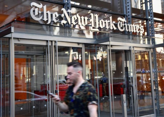 People walk with their smartphones in front of the New York Times building on September 6, 2018 in New York.A furious Donald Trump called September 5, 2018 for the unmasking of an anonymous senior official who wrote in the New York Times that top members of his administration were undermining the president to curb his 'misguided impulses.' Trump asked if the unsigned op-ed could be considered treasonous, assailed the newspaper for the 'gutless' piece and questioned whether the senior official it was attributed to actually existed. 'TREASON?' Trump posted in response to the article entitled 'I Am Part of the Resistance Inside the Trump Administration,' which claimed the president's own staff see him as a danger to the nation.'Does the so-called 'Senior Administration Official' really exist, or is / AFP PHOTO / ANGELA WEISS