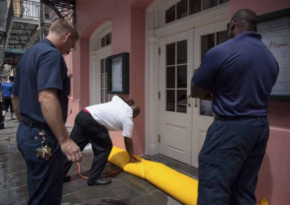 Workers place a flood barrier in front of a set of doors at the restaurant Brennan's in the French Quarter in New Orleans on July 11, 2019 in preperation for tropical storm Barry. - Tropical storm Barry barreled toward rain-soaked New Orleans on July 11 as the city hunkered down for an ordeal that evoked fearful memories of 2005's deadly Hurricane Katrina. (Photo by Seth HERALD / AFP)