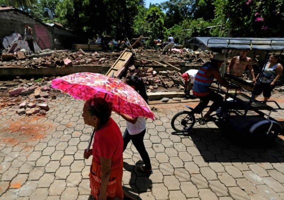 People walk next to debris after an earthquake in Community Tonala, el Viejo, Chinandega department, some 150km north of Managua on June 10, 2016.A strong 6.1 magnitude earthquake and at least four major aftershocks shook northwestern Nicaragua on Thursday night, triggering panic among residents and damaging some homes, officials said. There were no immediate reports of casualties. / AFP PHOTO / INTI OCON