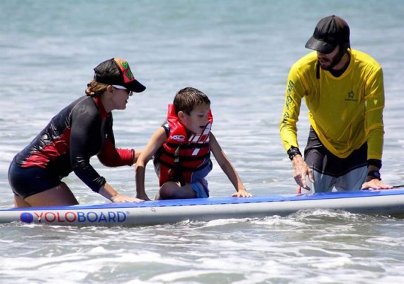 Un niño que padece autismo fue registrado al disfrutar de la brisa, las olas y la arena, durante una práctica terapéutica de surf en Ciudad de Panamá, Panamá). EFE