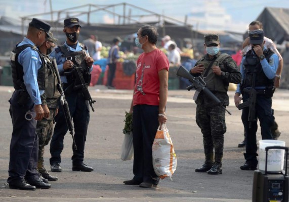 AME4812. TEGUCIGALPA (HONDURAS), 22/04/2020.- Un hombre con tapabocas habla este miércoles con oficiales tras salir de un mercado callejero autorizado por el gobierno, en Tegucigalpa (Honduras). El pico de contagios por COVID-19 en Honduras llegará probablemente a principios de junio, aseguró este miércoles la Organización Panamericana de la Salud (OPS), que señaló además que el distanciamiento social es la mejor forma de prevenir la enfermedad. 'Establecer el pico de contagio es muy difícil, pero según la mayoría de los cálculos se está hablando de principios o mediados de junio', dijo la representante de la OPS en Honduras, Piedad Huerta, en una entrevista con Efe. EFE/Gustavo Amador