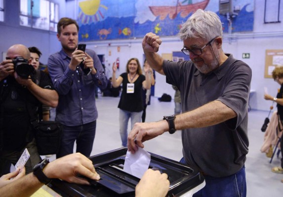 TOPSHOT - A man raises his fist as he casts his ballot in a polling station in Barcelona, on October 1, 2017, on the day of a referendum on independence for Catalonia banned by Madrid.More than 5.3 million Catalans are called today to vote in a referendum on independence, surrounded by uncertainty over the intention of Spanish institutions to prevent this plebiscite banned by justice. / AFP PHOTO / Josep LAGO
