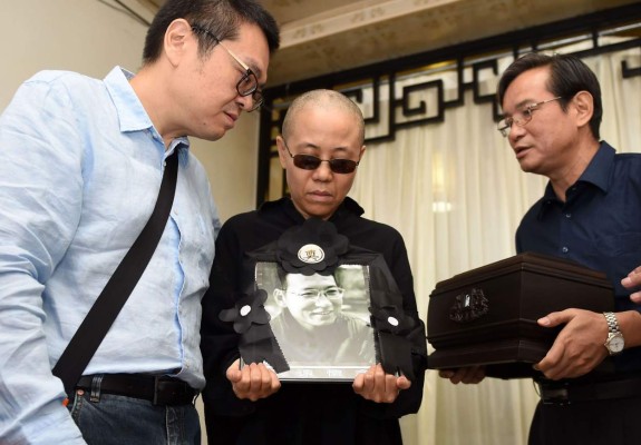 TOPSHOT - This handout photo provided by the Shenyang Municipal Information Office shows late Nobel laureate Liu Xiaobo's wife Liu Xia (C) and his brother, Liu Xiaoguang (L), holding a portrait of Liu Xiaobo and receiving the ashes (R) in an urn at a funeral parlour in the Chinese city of Shenyang, Liaoning province, on July 15, 2017.The body of China's late Nobel laureate Liu Xiaobo was cremated on July 15 after a private ceremony attended by his wife and friends, two days after the dissident lost a battle with cancer while in custody. / AFP PHOTO / Shenyang Municipal Information Office / Handout / -----EDITORS NOTE --- RESTRICTED TO EDITORIAL USE - MANDATORY CREDIT 'AFP PHOTO / Shenyang Municipal Information Office' - NO MARKETING - NO ADVERTISING CAMPAIGNS - DISTRIBUTED AS A SERVICE TO CLIENTS