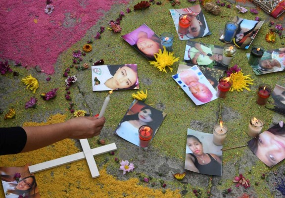 A woman lights a candle during a demonstration to demand justice for the 2016 murder of Honduran environmental activist Berta Caceres and 175 other women killed in the country so far this year, in front of the Public Ministry in Tegucigalpa, on July 4, 2017. / AFP PHOTO / Orlando SIERRA