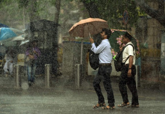 TOPSHOT - Indian pedestrians carry unbrellas as they walk through heavy rain showers in Mumbai on July 13, 2017. / AFP PHOTO / PUNIT PARANJPE