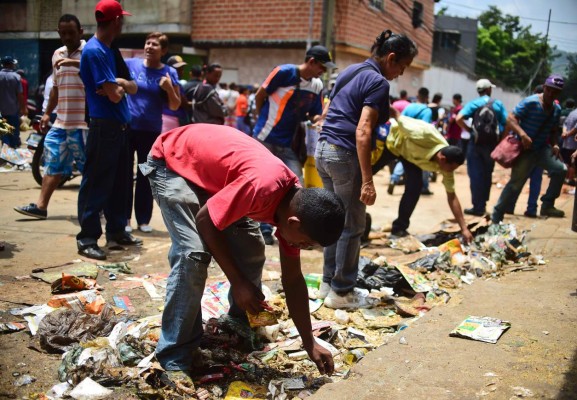 People look for food outside a looted supermarket at El Valle neighborhood, in Caracas, on April 21, 2017, after demonstrations against the government of Venezuelan President Nicolas Maduro.Venezuela was rocked overnight by fresh violence in anti-government protests that have now claimed nine lives in three weeks, as an official reported Friday the fatal shooting of another man. / AFP PHOTO / RONALDO SCHEMIDT