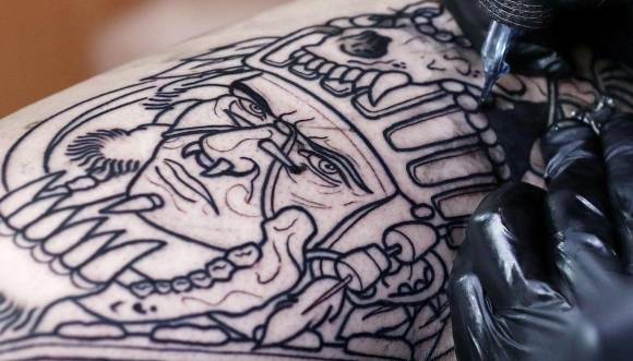 Una persona se tatúa un dibujo con tinta negra en una pierna.