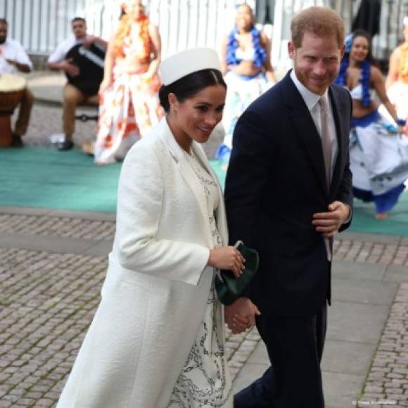 Meghan, que fue una de las primeras en llegar de la mano de su esposo, el príncipe Harry, usó un elegante conjunto, un vestido blanco estampado de cadenas, abrigo, bolso y zapatos Victoria Beckham.
