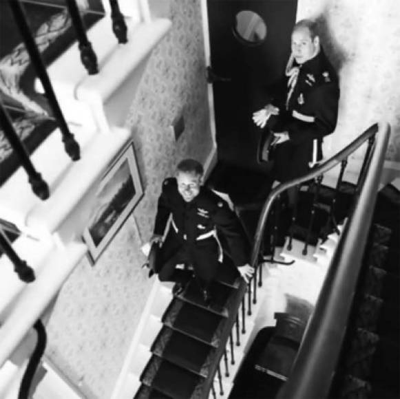 El príncipe Harry sonríe para la cámara mientras baja las escaleras rumbo a la iglesia, detrás de él, su hermano el príncipe William.