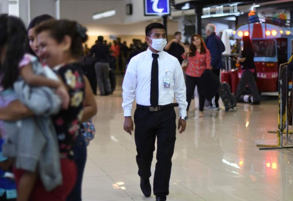A Guatemalan immigration official wears a face mask as a precaution against the spread of the new coronavirus, at La Aurora International Airport in Guatemala City, on March 12, 2020. (Photo by Johan ORDONEZ / AFP)