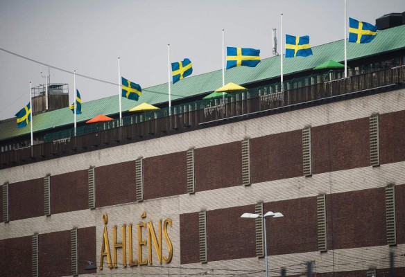 Sweden's national flags at half-mast are pictured on the roof of the Ahlens department store where a truck drove into in Stockholm, Sweden, on April 10, 2017.Four people died and fifteen were injured when a truck plunged into a crowd at a busy pedestrian street in the Swedish capital on April 7, 2017. / AFP PHOTO / Jonathan NACKSTRAND