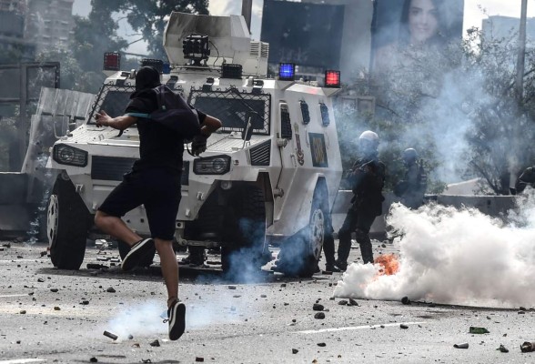 An opposition activist clashes with the riot police during a march against Venezuelan President Nicolas Maduro held on May Day, in Caracas on May 1, 2017. Venezuela's beleaguered President Nicolas Maduro on Monday called for a new constitution, to be written by a 'people's' body circumventing the opposition-held Congress. The decree was to 'block the fascist coup' threatening the country, he told thousands of supporters in Caracas at a May Day rally. / AFP PHOTO / Juan BARRETO