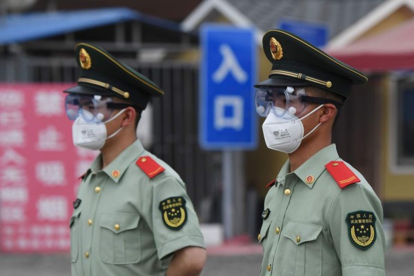 Paramilitary police officers wear face masks and goggles as they stand guard at an entrance to the closed Xinfadi market in Beijing on June 13, 2020. - Eleven residential estates in south Beijing have been locked down due to a fresh cluster of coronavirus cases linked to the Xinfadi meat market, officials said on June 13. (Photo by GREG BAKER / AFP)