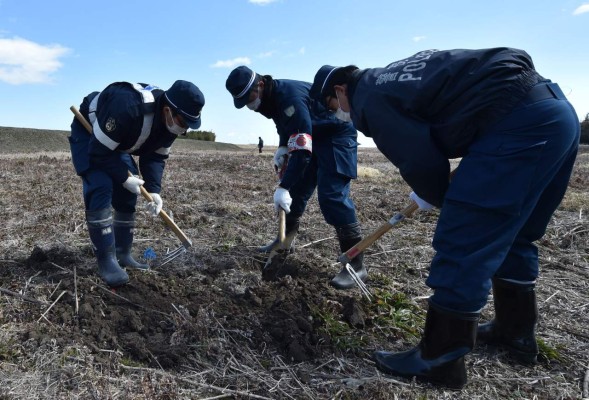 Policemen search for missing people of the 2011 quake-tsunami disaster in Namie, a no entry zone in Fukushima prefecture on March 11, 2017.Japan is marking on March 11 the sixth anniversary of the magnitude 9.0 quake which struck under the Pacific Ocean and the ensuing tsunami which left about 18,500 people dead or missing. / AFP PHOTO / KAZUHIRO NOGI