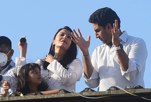 (FILES) In this file photo taken on March 22, 2020 Bollywood actors Abhishek Bachchan (R) and Aishwarya Rai Bachchan along with their daughter Aaradhya clap from atop a residential building to thank essential service providers during a one-day Janata (civil) curfew imposed amid concerns over the spread of the COVID-19 novel coronavirus, in Mumbai. - Bollywood superstar Aishwarya Rai has tested positive for the coronavirus, a Mumbai city authority official told AFP on July 12, just a day after her father-in-law Amitabh Bachchan said he was in hospital with the infectious disease. Her eight-year-old daughter, Aaradhya, was also COVID-19 positive, the Brihanmumbai Municipal Corporation official, who asked to remain anonymous, said. (Photo by Sujit Jaiswal / AFP)
