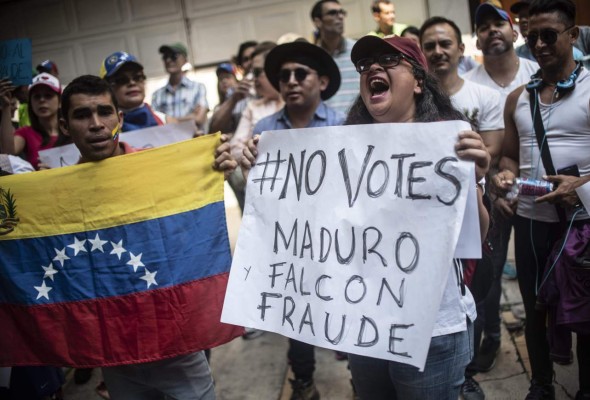 Members of the Venezuelan community in Mexico protest against the presidential election in their country, in front of the Venezuelan embassy in Mexico where a polling station was installed, in Mexico City, on May 20, 2018.Venezuelans, reeling under a devastating economic crisis, began voting Sunday in an election boycotted by the opposition and condemned by much of the international community but expected to hand deeply unpopular President Nicolas Maduro a new mandate. / AFP PHOTO / PEDRO PARDO