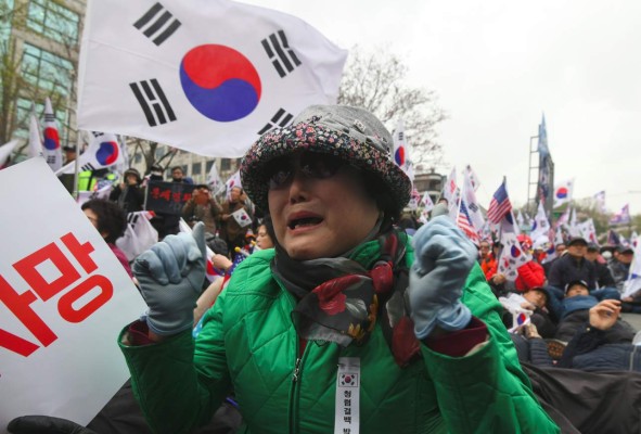 A supporter of South Korea's former President Park Geun-hye cries after a court sentenced Park Geun-hye to 24 years in prison, during a rally outside the Seoul Central District Court in Seoul on April 6, 2018.South Korea's disgraced former president Park Geun-hye was jailed for 24 years on April 6, for corruption, closing out a dramatic fall from grace for the country's first woman leader who became a figure of public fury and ridicule. / AFP PHOTO / Jung Yeon-je