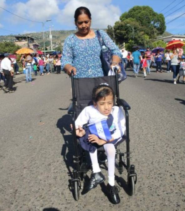 Sin importar sus condiciones físicas, varios menores decidieron desfilar. En la imagen, una niña con discapacidad en sus piernas es conducida por su madre durante los desfiles de este domingo.