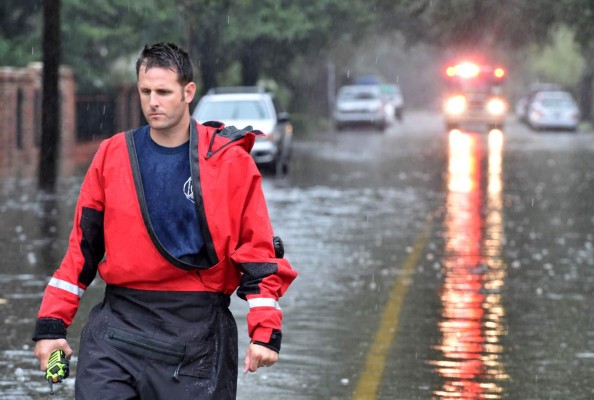 A firefighter walks in front of his truck on a flooded street in downtown Charleston, SC on October 04, 2015. Relentless rain left large areas of the US southeast under water and forecasters warned that more heavy downpours could trigger historic flooding in the crucial next 24 hours. The states of North and South Carolina have been particularly hard hit, but the driving rain in recent days has spared almost none of the US East Coast and forecasters say the worst is not over quite yet. News reports blamed the wild weather on four deaths in the United States since Thursday, all in the Carolinas. AFP PHOTO/MLADEN ANTONOV
