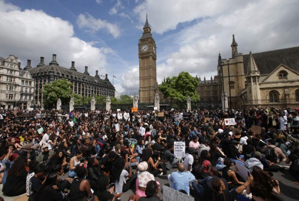 Demonstrators from the Black Lives Matter movement sit in the road on Parliament Square in central London on July 10, 2016, during a demonstration against the killing of black men by police in the US. Police arrested scores of people in demonstrations overnight Saturday to Sunday in several US cities, as racial tensions simmer over the killing of black men by police. / AFP PHOTO / DANIEL LEAL-OLIVAS