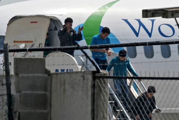 Honduran migrants get off a plane as they arrive at the Ramon Villeda Morales airport in San Pedro Sula, 180 km north of Tegucigalpa, on April 11, 2019, after being deported from the US. - By the end of March, 19,605 Hondurans had been deported this year, according to the General Direction of Honduran Migrant Protection. (Photo by Orlando SIERRA / AFP)